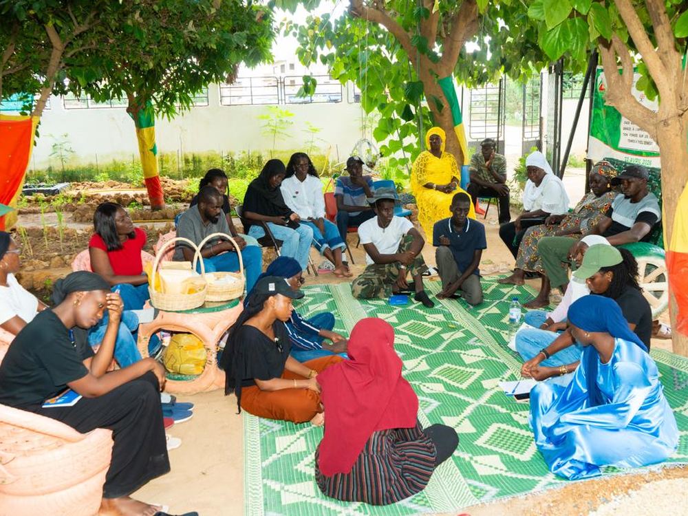 Académiciens assis sur une natte avec des femmes formées à l'agroécologie, à Thiès