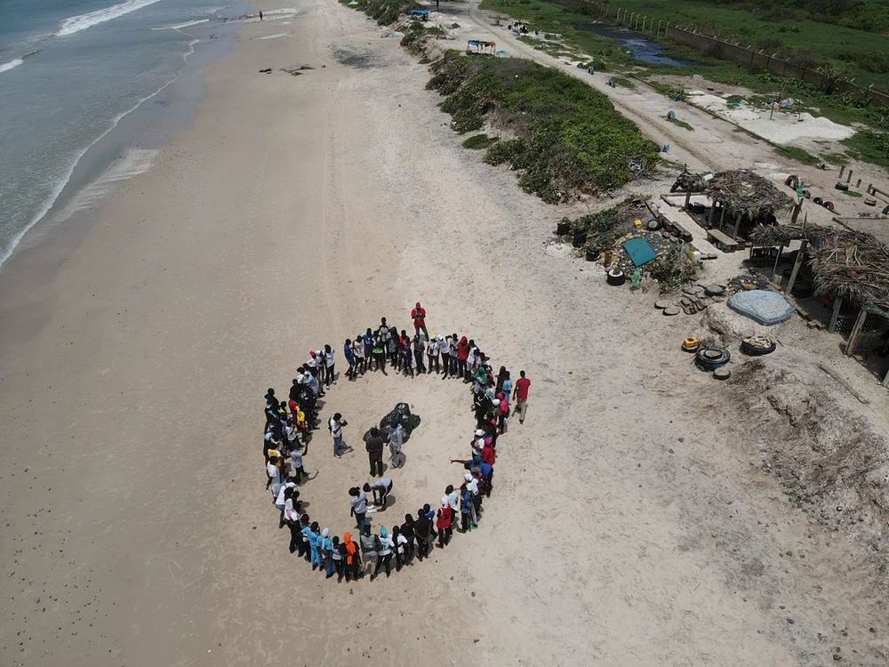 Vue aérienne de participants formant un grand cercle sur la plage