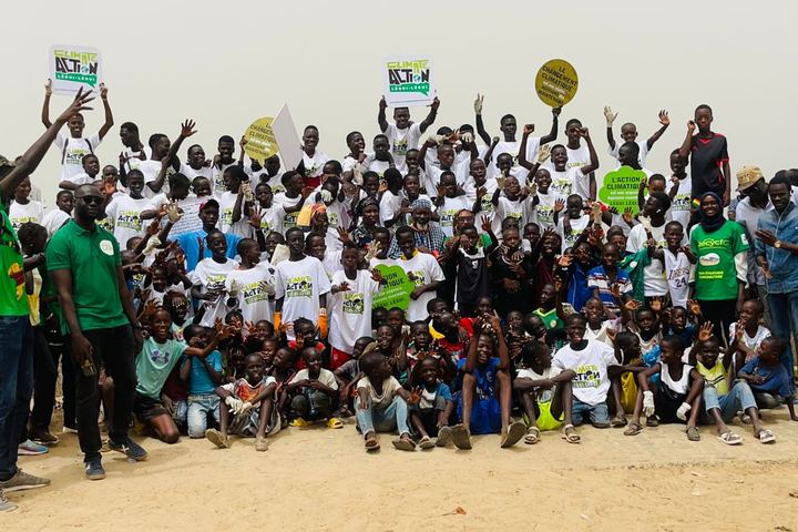 Une centaine de jeunes en t-shirts verts rassemblés sur une plage